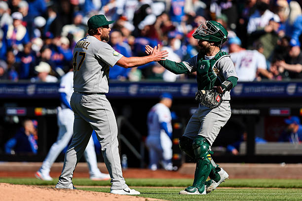 Joel Kuhnel and Shea Langeliers of the Athletics celebrating a win and sweep over the Mets