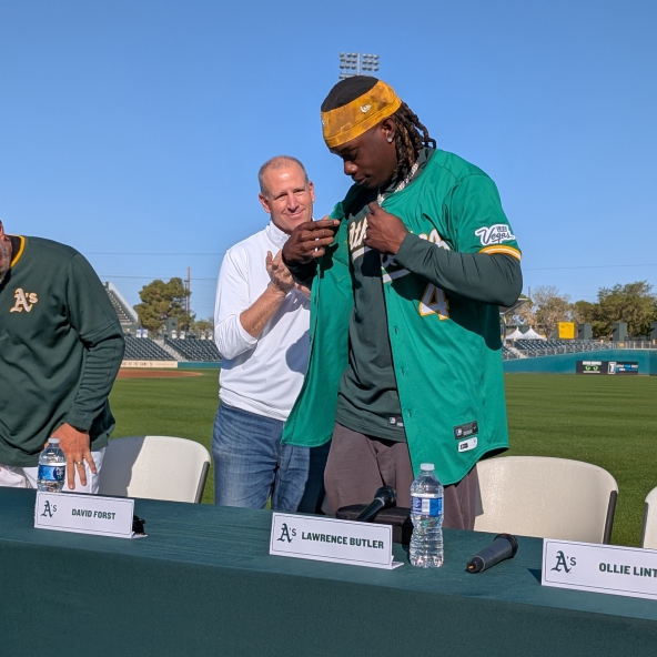 Lawrence Butler putting on an Athletics jersey at the press conference announcing his contract extension