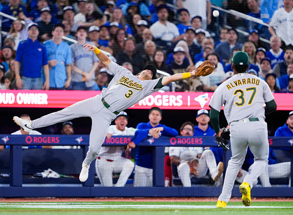 Max Muncy of the Athletics stretching for and missing a foul fly ball against the Blue Jays