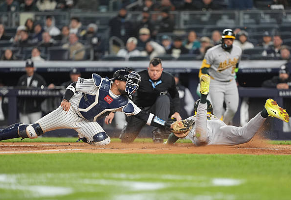 Lawrence Butler of the Athletics diving in to score against the Yankees.