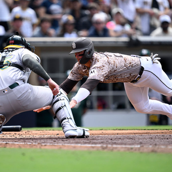 Athletics catcher Jonah Heim tagging out the diving Ty France of the Padres