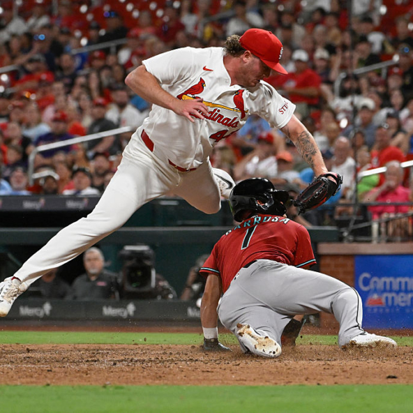 Jorge Barrosa of the Diamondbacks diving in safely for a run as Cardinals pitcher Gordon Graceffo tries in vain to tag him out